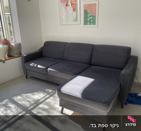 ספה אפורה עם מגב ומטלית כחולה על הרצפה